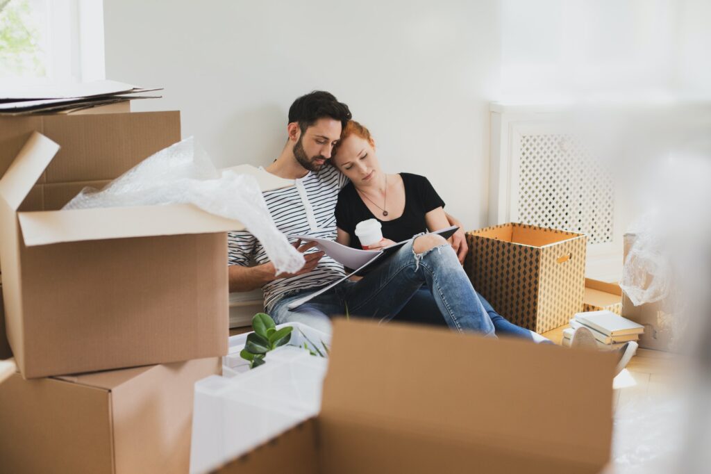 Happy marriage packing stuff into carton boxes while moving-out
