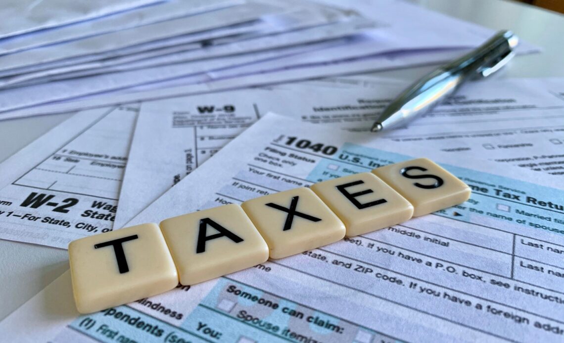 Low angle of letter tiles with the word TAXES on a variety of tax forms.