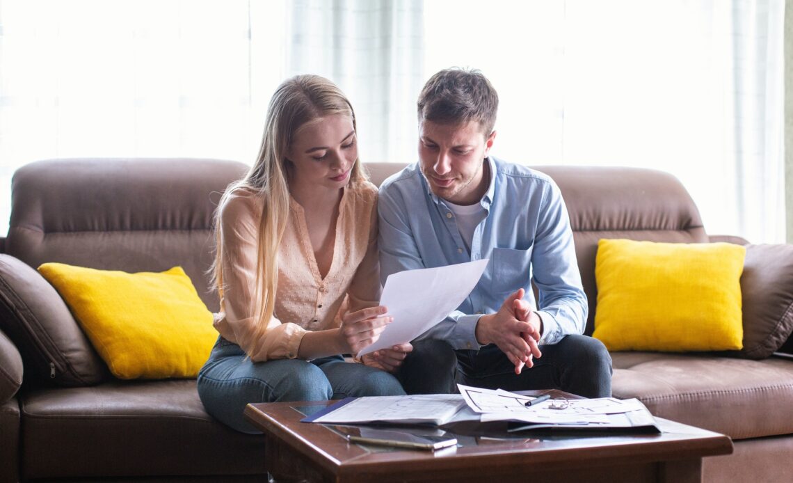 Young married couple looking through tenancy agreement in house for sale