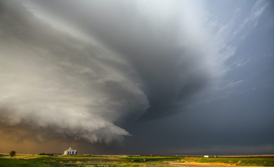 A tornado-producing supercell thunderstorm spinning over ranch land at sunset near Leoti, Kansas