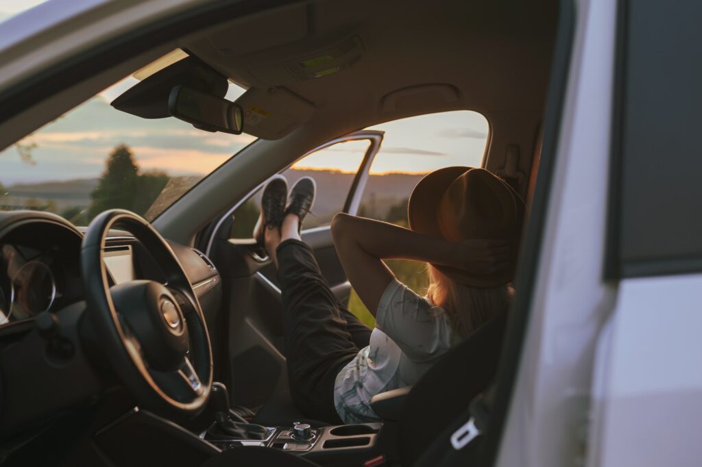 Anonymous young blonde woman in hat sitting in a rental car
