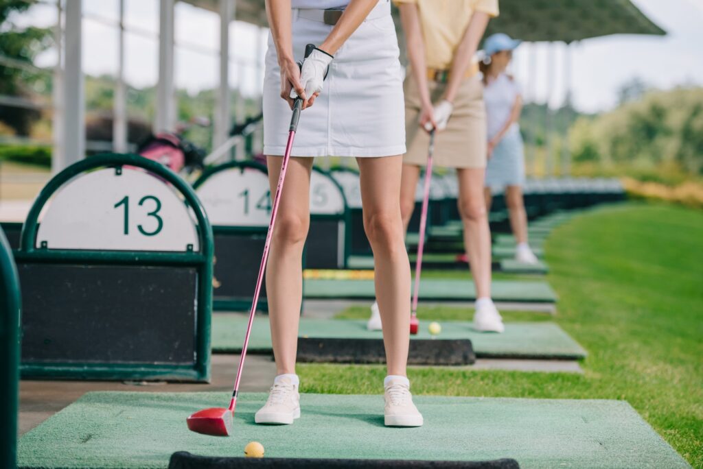 partial view of women with golf clubs playing golf at golf course