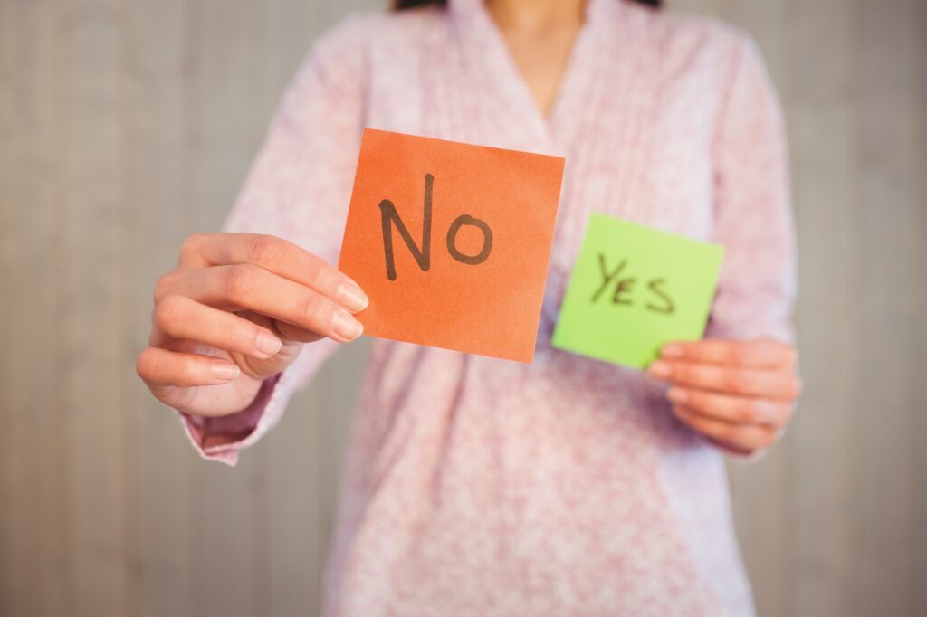 Woman holding yes and no cards on wooden planks background