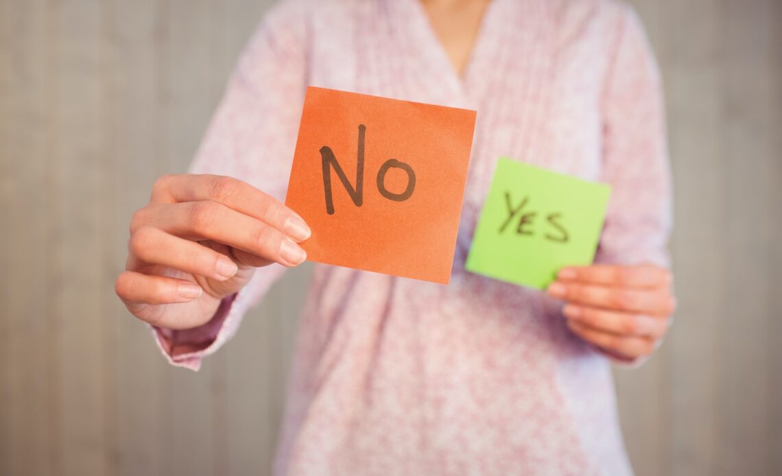 Woman holding yes and no cards on wooden planks background