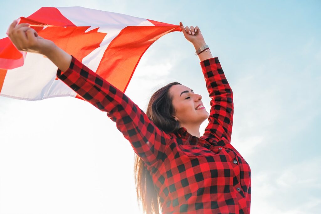 Young millennial brunette woman holding The National Flag of Canada. Canadian Flag or the Maple Leaf