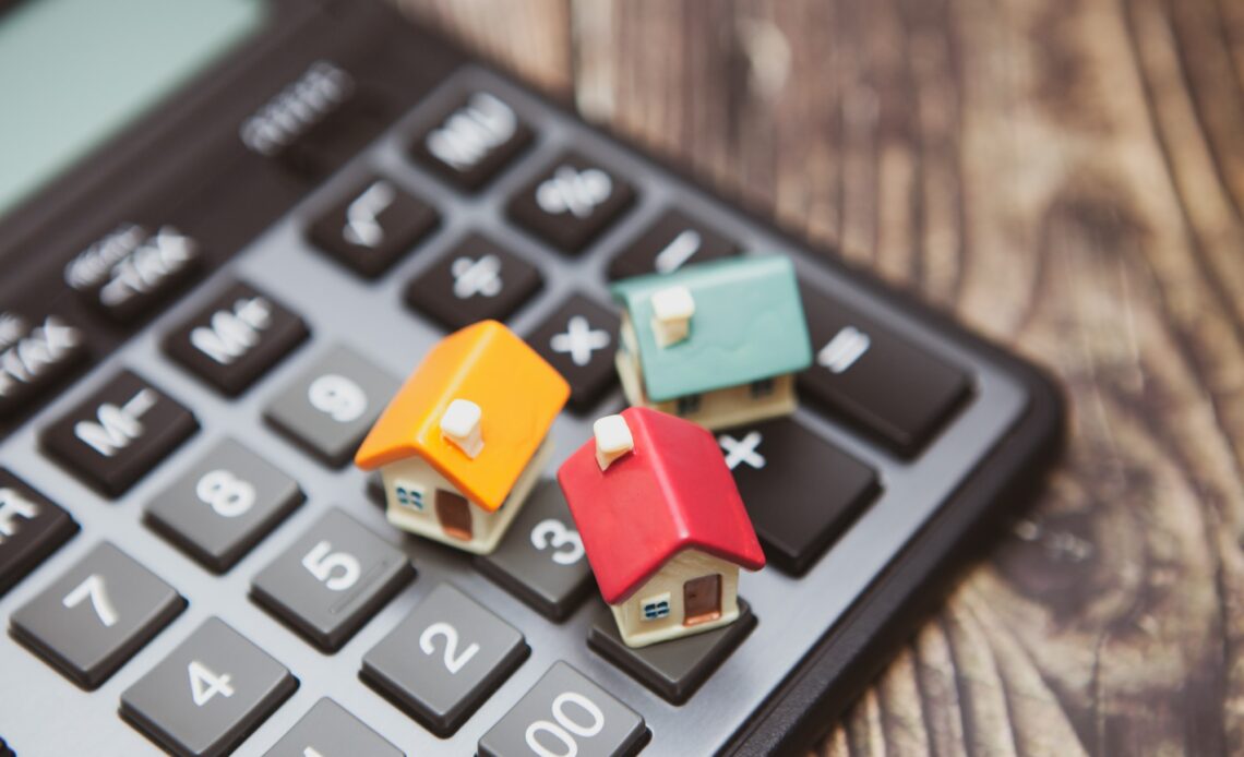 A calculator and several colored houses. The concept of buying a home on credit or a mortgage