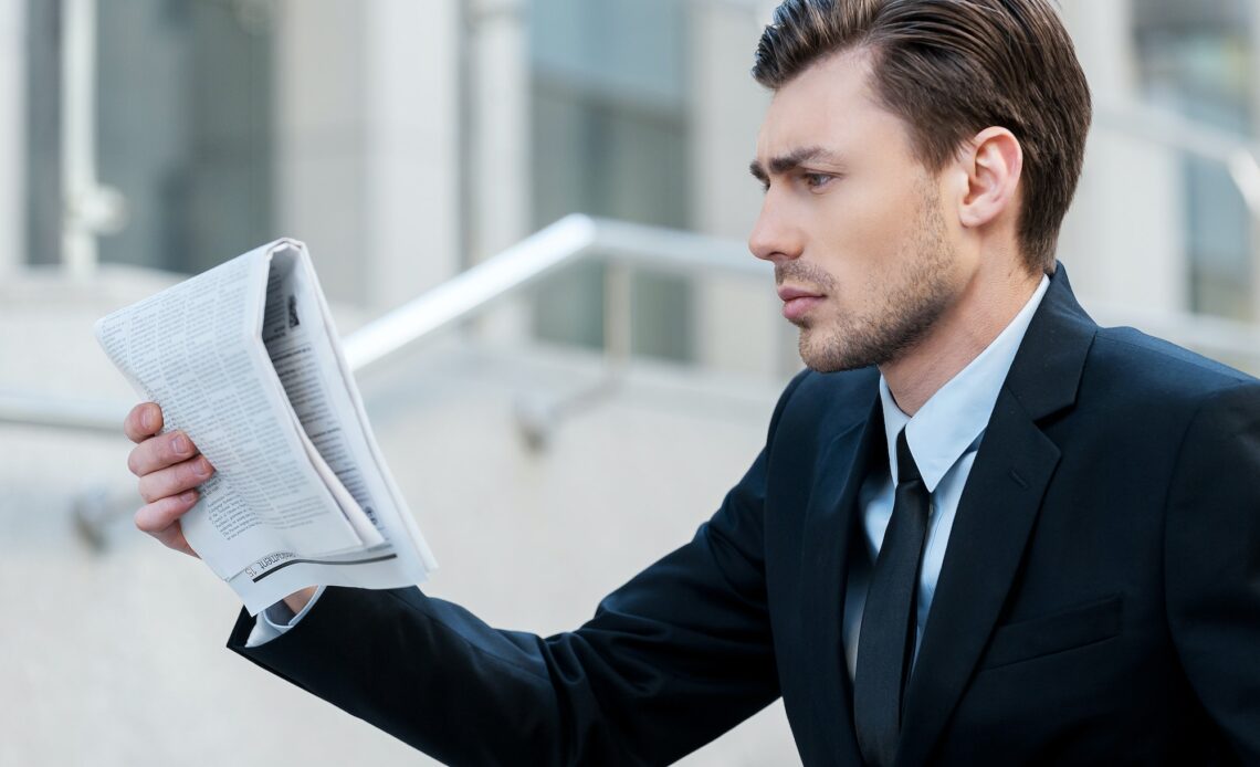 Fresh news. Young businessman reading the newspaper