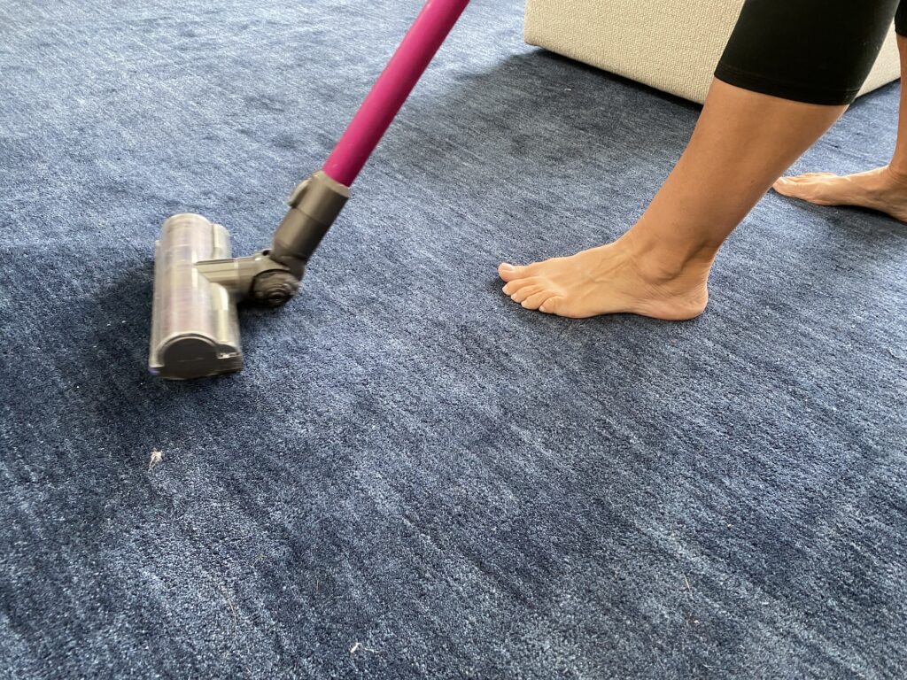 Vacuuming the blue carpet with the pink vacuum cleaner