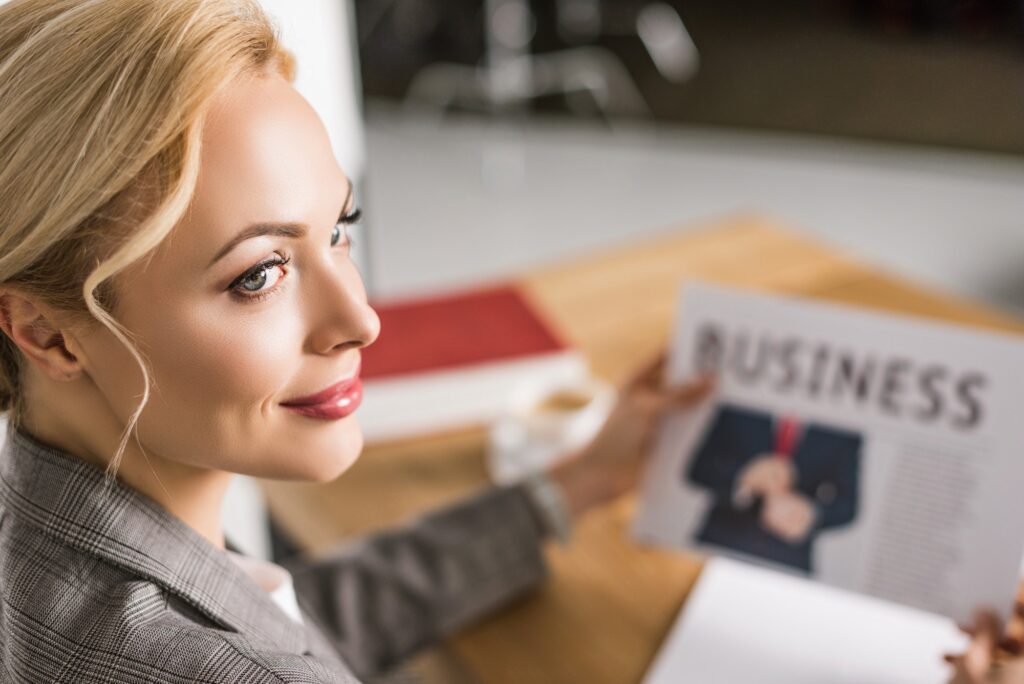 selective focus of businesswoman with newspaper at workplace